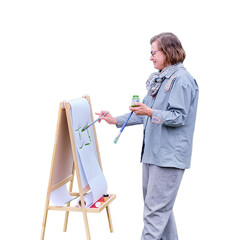 Happy woman draws on the easel with a brush and paints, isolated on a white background. Woman...