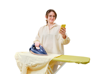 A happy woman irons things with dark blue iron and a mobile phone, isolated on a white background
