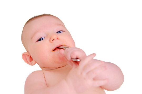 Infant baby himself holds a spoon with his hands and puts it in his mouth, isolated on a white background. Kid aged four months