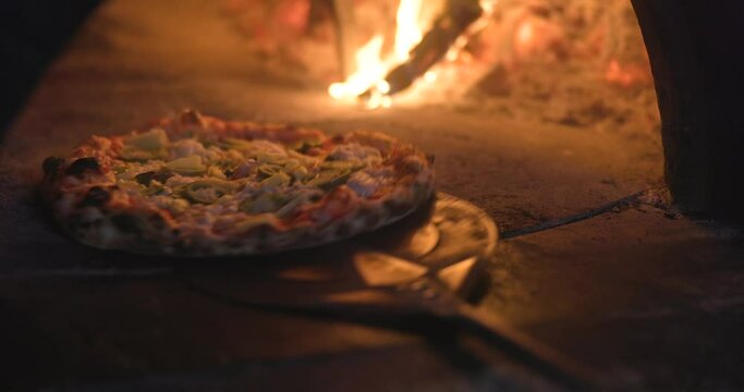Baking the smoking hot delicious pizza in a traditional Italian oven with wood fire flame. Spin and turn, pull in and pull off in slow motion. 