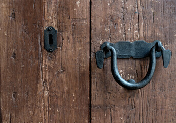 Black old door handle and door lock over a brown wooden door