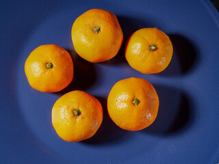 one orange mandarin on blue plate