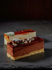 Three chocolates cake with chocolate drips on a black background. Layered cake with milk, black and white chocolate souffle decorated with strawberries on top. Confectionery background with copy space