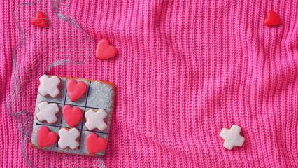 Tic tac toe gingerbread. Pink knitted background. Valentine Day