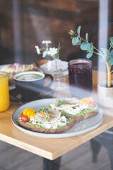 Avocado and egg toast with bean sprouts and tomatoes on a white plate in a breakfast restaurant. Vegetarian and healthy food.