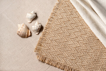 Minimal aesthetic neutral summer vacation concept with sea shells, jute rug and linen cloth on a beige background, copy space
