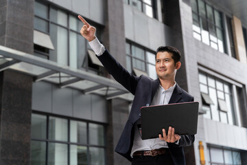 Asian business man holding laptop and Point your finger forward to show leadership in marketing in...