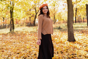 Happy young woman having fun, walking in autumn park. Relaxation, enjoying, solitude with nature concept.