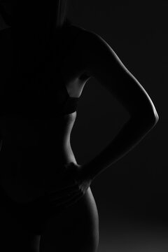 Female nude silhouette in lingerie. Young slim sexy woman. Girl with naked body. Black and white silhouette of female body art photography. Unrecognizable without a face