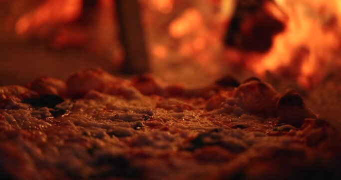 Macro close up of cheese oil bubbles baking the smoking hot delicious pizza in a traditional Italian oven with wood fire flame.