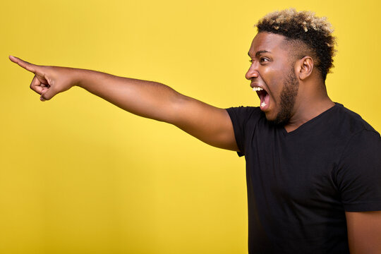 Disgruntled Curly Guy Kicks The Enemy Out Of The Room, Pointing Him To The Door. An Indignant Black Young Man Menacingly Points His Finger At Another Person And Shouts Loudly. 