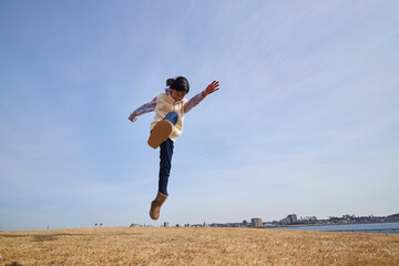 冬の海岸の公園で元気で跳んで遊ぶ小学生の女の子の様子