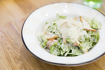 Close up of Caesar salad in a big white plate  in a cafe