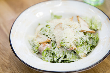 Close up of Caesar salad in a big white plate  in a cafe
