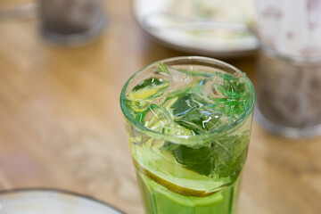 Green fresh mojito in transparent glass on table as summer party drink