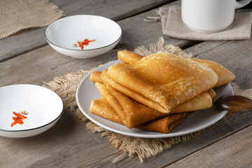 A stack of fried pancakes on an old wooden table. Maslenitsa, traditional Russian blini