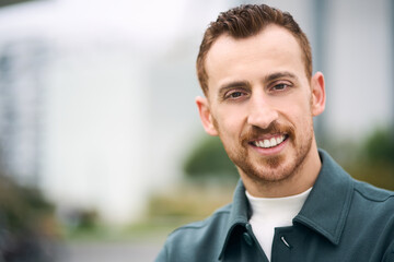 Happy handsome modern man smiling toothy to camera while posing outdoors