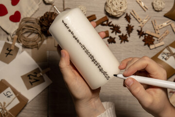 Unrecognizable young woman paint numbers on candles. Female making homemade advent calendar Made with your own hands step by step DIY crafts do it yourself. Preparation to christmas concept. Seasonal