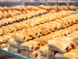 Image of baked goods behind glass on a shelf .