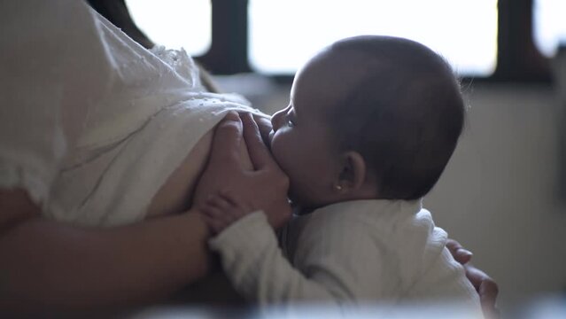 Beb&eacute; tomando leche de pecho de mam&aacute; en posici&oacute;n de caballito