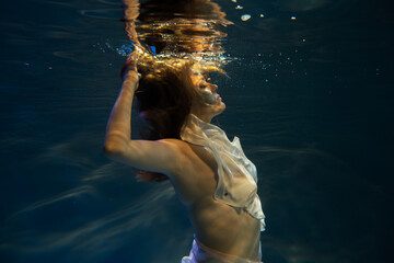 Young beautifull caucasian woman in dress under water