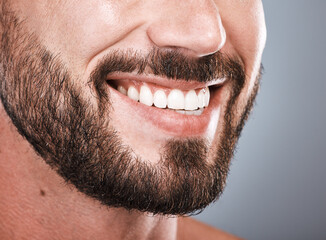 Smile, dental health and mouth of a man with teeth isolated on grey studio background. Happy, showing and beard of a model with results from tooth whitening, dentist cleaning and hygiene on backdrop