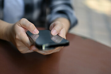 Close-up image of a female sits at table using her smartphone, chatting, using mobile app