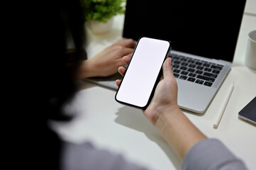 Close-up, back view of a female worker using her smartphone at her desk. mobile phone mockup.