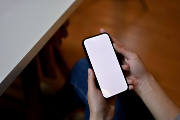 Top view of a female using her smartphone at her desk. phone white screen mockup