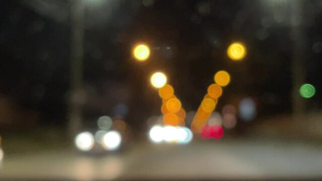 Blurred car lights bokeh in the evening city. Defocused headlights and street lighting at night. Moving bokeh circles of cars at night. Blurred city traffic background