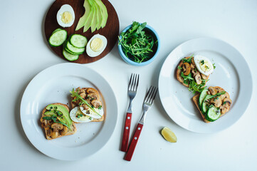 various morning vegetarian toast set with mushrooms, avocado, arugula, cucumber and eggs. Healthy food on white background
