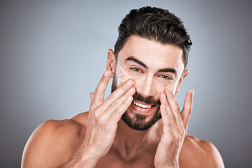 Face portrait, skincare and man with cream in studio isolated on a gray background for facial wellness. Cosmetics, dermatology or happy male model with lotion, creme or moisturizer product for health