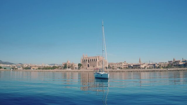 drone shot of a sailboat anchoring in front of cathedral de Mallorca
