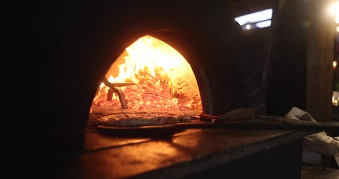 Baking the smoking hot delicious pizza in a traditional Italian oven with wood fire flame. Spin and turn, pull in and pull off in slow motion. 