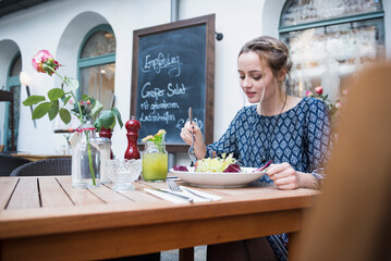 Young woman eating salad at restaurant
