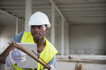 Construction worker holding digital tablet and iron bars at building site