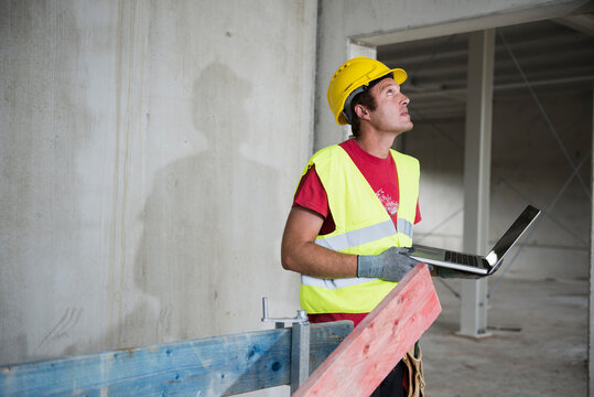 Construction worker with laptop at building site