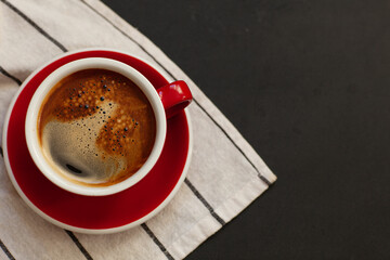 Coffee concept, red cup of coffee on a black background with space for text, top view