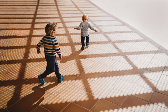 Back view of young children running on gazebo shadows