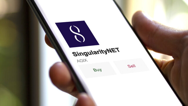 February 07 2023 London UK. An investor's analyzing the SingularityNET  coin on screen. A phone shows the crypto's prices to invest