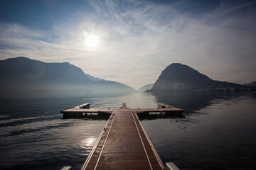 Autumnal dramatic down from mooring in the Lugano lakefront with San Salvatore peak and Italian mountains in the background, Switzerland. Concept about serenity and relaxation