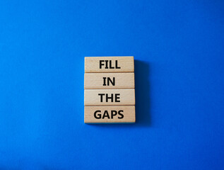 Fill in the gaps symbol. Concept words fill in the gaps on wooden blocks. Beautiful blue background. Business and fill in the gaps concept. Copy space.