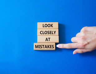 Look closely at mistakes symbol. Wooden blocks with words Look closely at mistakes. Businessman hand. Beautiful blue background. Business and Look closely at mistakes concept. Copy space.