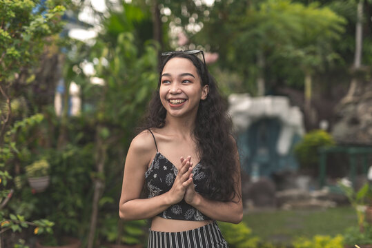 A pretty and inspired young Filipina woman with curly hair wearing a nice black top and long skirt at the garden.