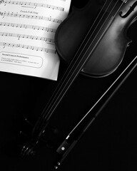 violin and bow with sheet music on black background © Donagh