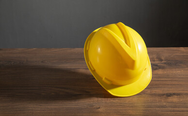 Yellow construction helmet on the wooden table.
