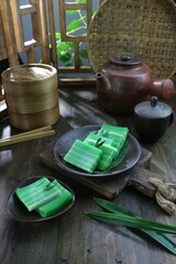 two plates of green steamed layer cakes on rustic wooden table