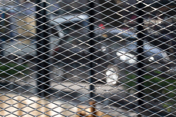 wire mesh fence with vehicles in the background