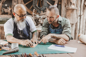 master of leather tailor teaching and training young man for making handcraft leather pouch