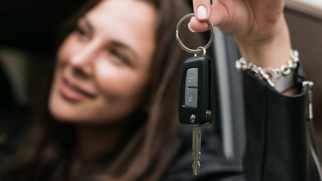 Close-up of the keys to the new car in the hands of a young woman. Happy buyer